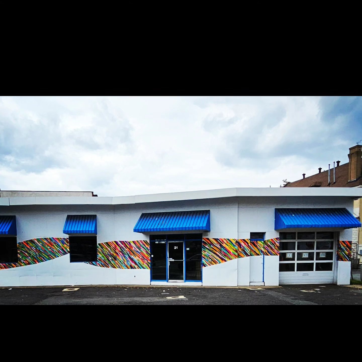 Da Race - building facade with blue awnings and mural stripe