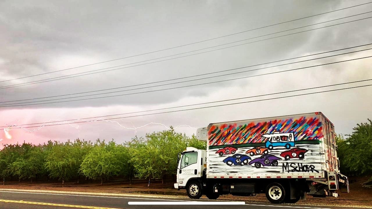 Da Race Moving - art truck on stormy desert road with lightning